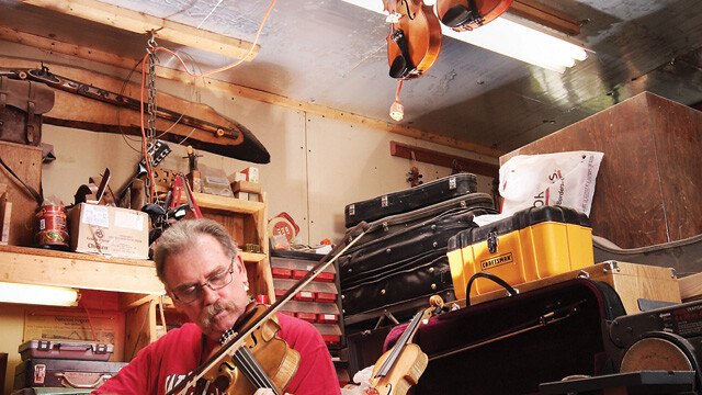 THE VIOLIN IS IN. Scott Hootman slides a bow across one of his stringed creations inside his Plum Street workshop. Hootman has been making violins since 1985. Hootman is a third-generation instrument craftsman.