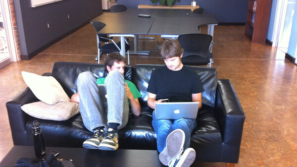 Software Architect Ryan Yohnk and co-founder Zach Halmstad work together on a couch in the JAMF Software office. The company encourages alternative workspaces and has very few offices in its building to encourage a relaxed atmosphere.