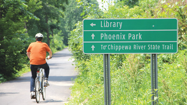 LOOKING FOR A SIGN?  Several additional bicycle and pedestrian signs were installed in late June throughout parts of Eau Claire’s paved trail network. The trails wind around the city and on several paths throughout downtown along rivers and lakes. Helping illustrate how well-connected the Valley really is for recreational biking, the new signs point the way to nearby locations like parks and libraries, but also to further away destinations like Altoona and Chippewa Falls.