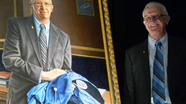YOU OUGHT TO BE IN PICTURES. Outgoing UW-Stout Chancellor Charles Sorensen posed in May with a portrait painted by retired art professor Doug Cumming.