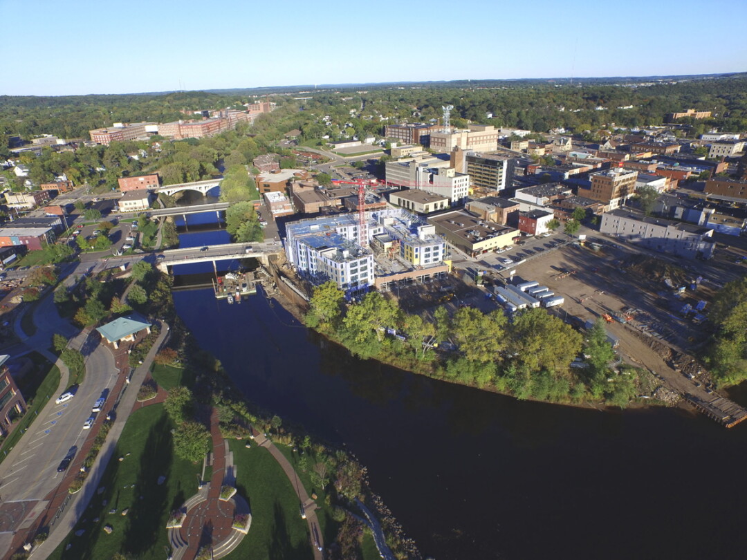DRONE’S-EYE VIEW. The future site of the Confluence Arts Center, right foreground, is next to the mixed-use building rising on South Barstow Street, center, in downtown Eau Claire. Image: COREY DRIVAS/MARKET & JOHNSON