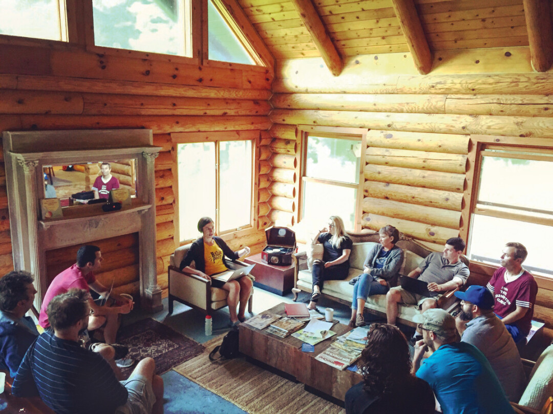 CABIN FEVER. Wisconsin Life producer Erika Janik (in yellow T-shirt), of Wisconsin Public Radio, hosts a group of regional writers for a weekend workshop on writing for radio and podcasts. A series of these residencies are produced by the new Chippewa Valley Writers Guild and held at a log cabin in Fall Creek called Cirenaica. Read more in the editors note from Nick Meyer below.