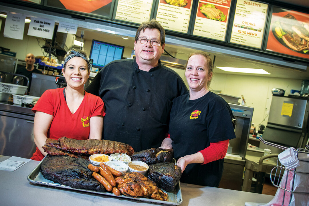 LOW AND SLOW UNTIL IT’S GOOD AND READY. Karl Hartkemeyer (center), owns Karl’s Bar-B-Q Express in Chippewa Falls. The menu features brisket, ribs, and turkey – and chicken’s on the way.