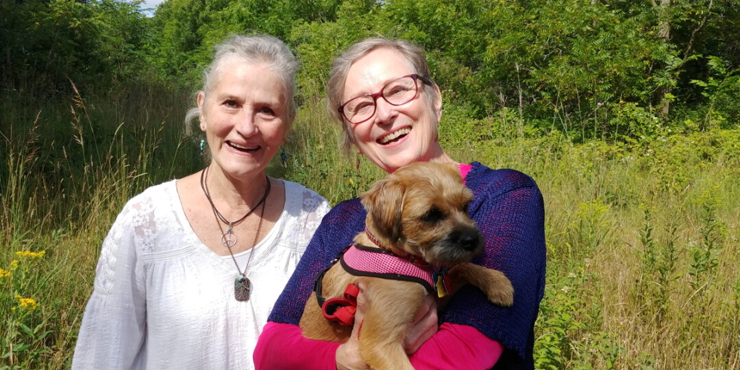HOW THE WEST WAS FUN. Cheryl Leonard (left) and Diane Omtvedt (right), of Eau Claire’s Upper Westside neighborhood, often take their pooches for easy strolls through the forested parcel between 11th Street, the High Bridge Trail, and Bolles Street. Also pictured is By Golly Miss Molly, Diane’s furry companion.