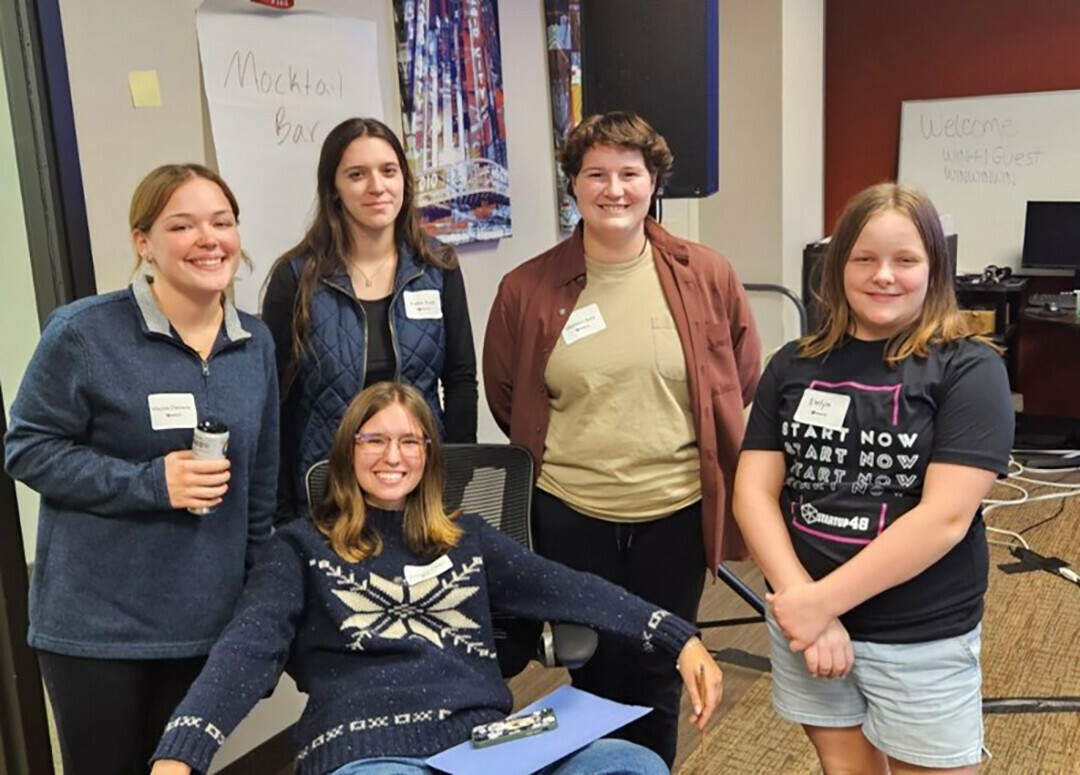 The Startup 48 Mocktails winning team relaxed for a post-victory photo. From left to right: University of Wisconsin-Eau Claire students Maysa Clemens, Kaitlin Koch, Theresa Kaser, seated, and Madison Bohl, with Evelyn White, 6th grade Startup 48 weekend helper.