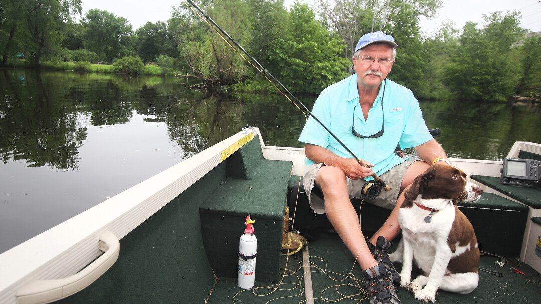 FISHFUL THINKING. Dave Carlson (shown here fly fishing at Eau Claire’s Riverview Park with his dog Ellie) published his latest book, A Fish Gift, in April.