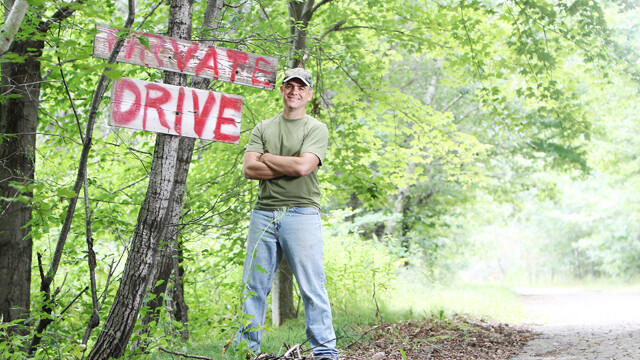 ON THE PATH. Perry (shown here trespassing next to his “vernacular” sign) has published five books with Harper-Collins. 