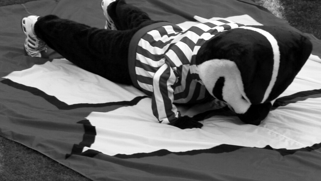 FLAT ON HIS FACE. Sure, Bucky looks like he’s doing a post-touchdown push-up, but he’s also demonstrating the position the Badgers find themselves in when it comes to football and men’s basketball championships.