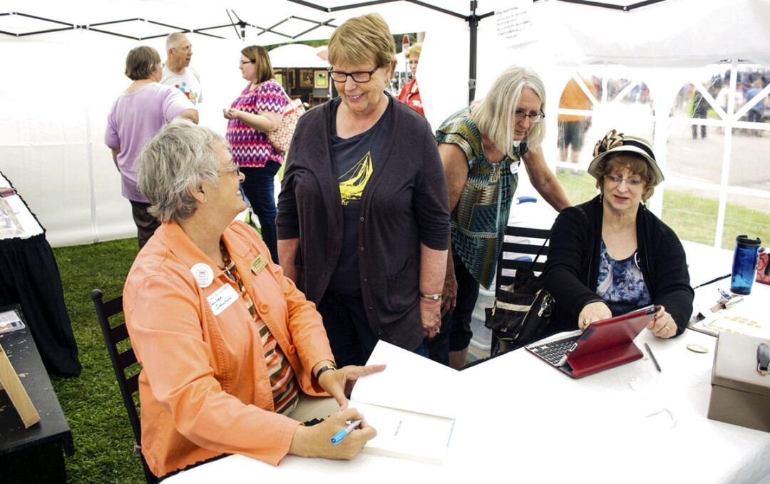 AND WHO SHOULD I MAKE THAT OUT TO? Sandra Stanton, a member of Chippewa Valley Local Authors, autographs a book inside a sales tent the group set up at the Festival in the Pines last month in Eau Claire.