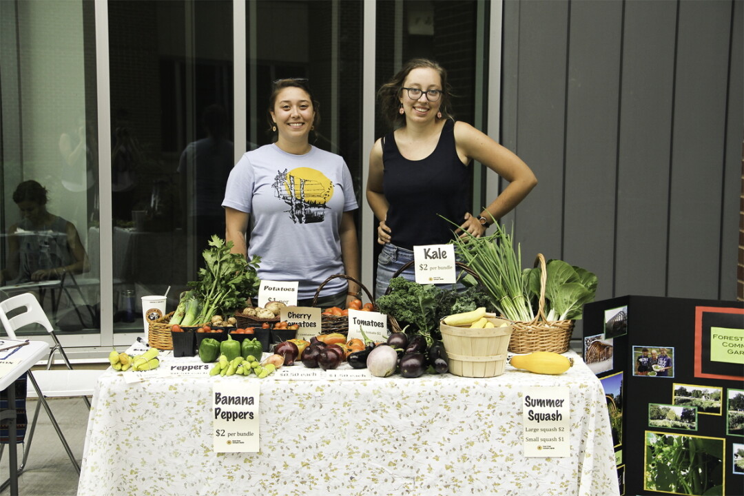 OH MY SQUASH! Kate Beaton (left) and Marni Kaldjian (right) display community-grown veggies at the first-ever UWEC Centennial Campus Market earlier this month.