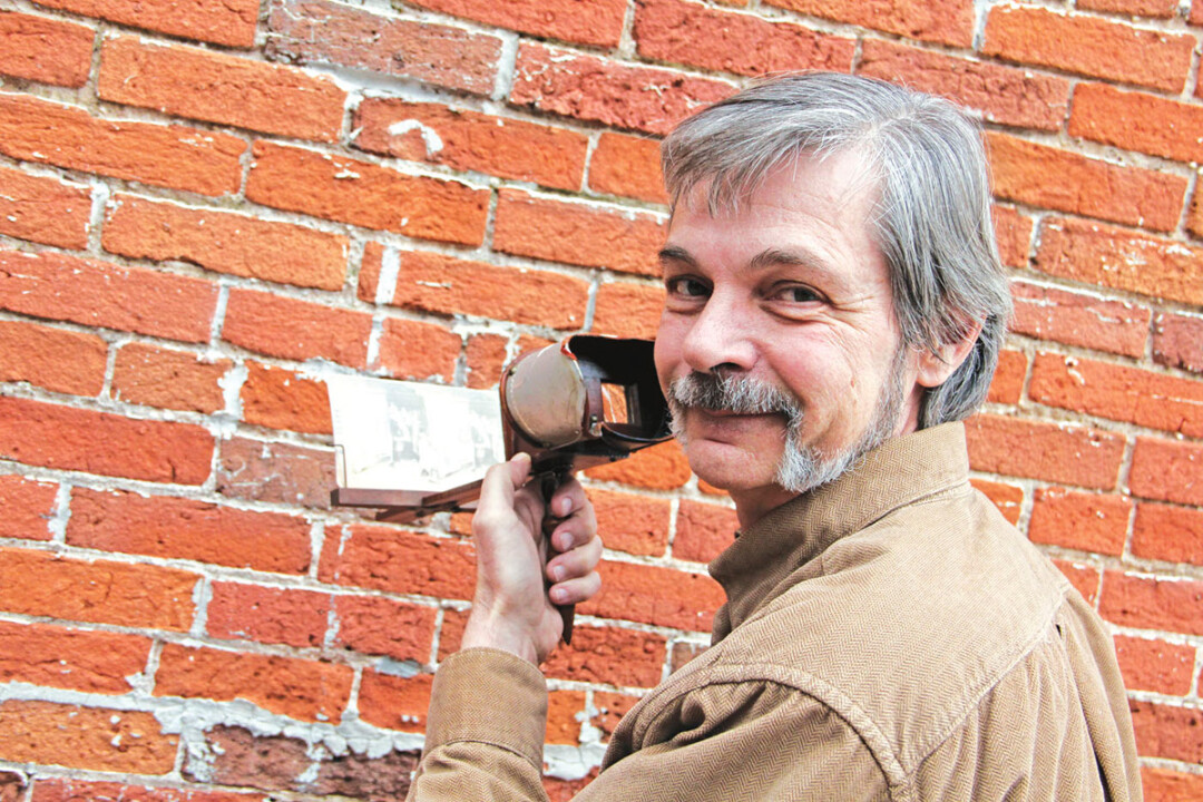 VICTORIAN ERA VIRTUAL REALITY GOGGLES. Author David Tank shows off a vintage stereoscope containing one of the 19th century Christmas images that inspired his new book for young readers, Secret Santa.