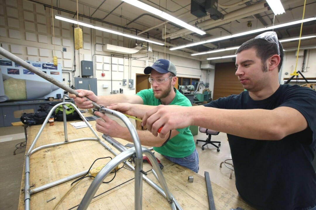Engineering students Jordan Reidt, left, and Todd Tollefson work on the Buvala Fence Cart. They helped redesign the cart for inventor Matthew Buvala.