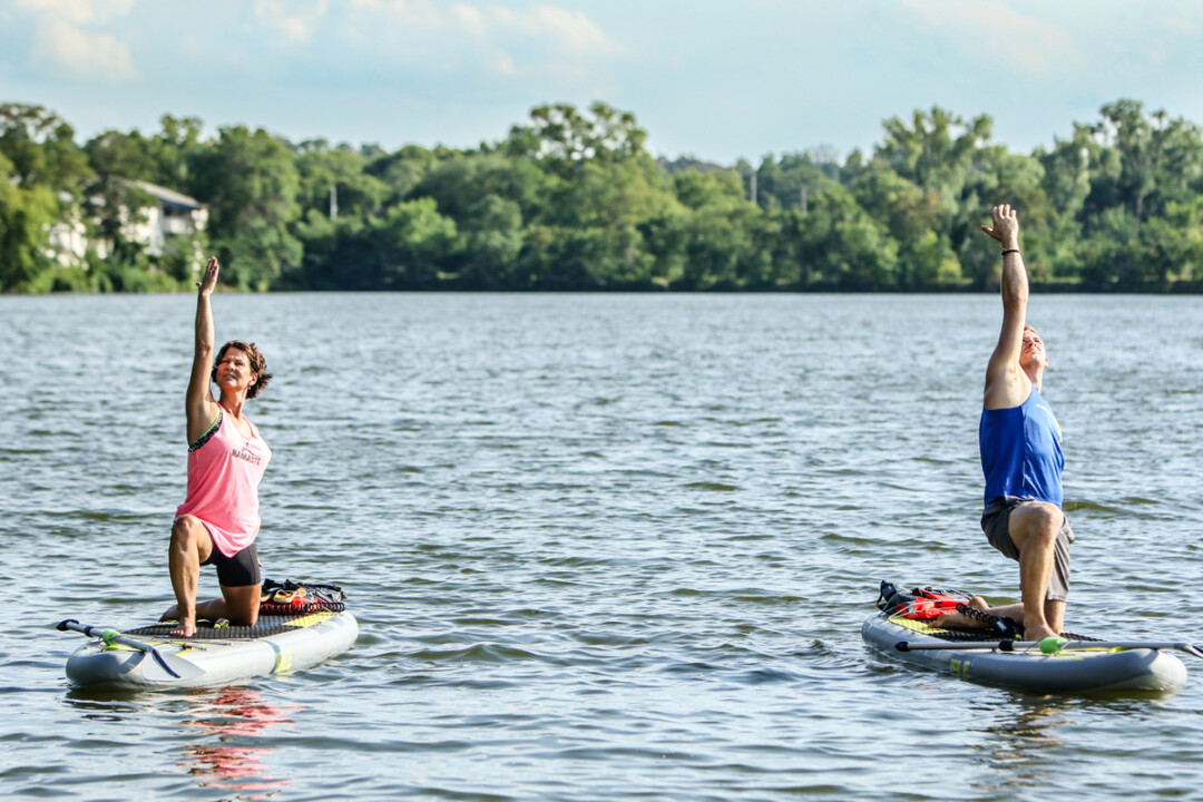 WHATEVER FLOATS YOUR PADDLEBOARD. Sandy LaValley, owner and instructor at Floating Bliss Yoga, takes her classes out to various bodies of water around the area to practice yoga on stand up paddleboards.