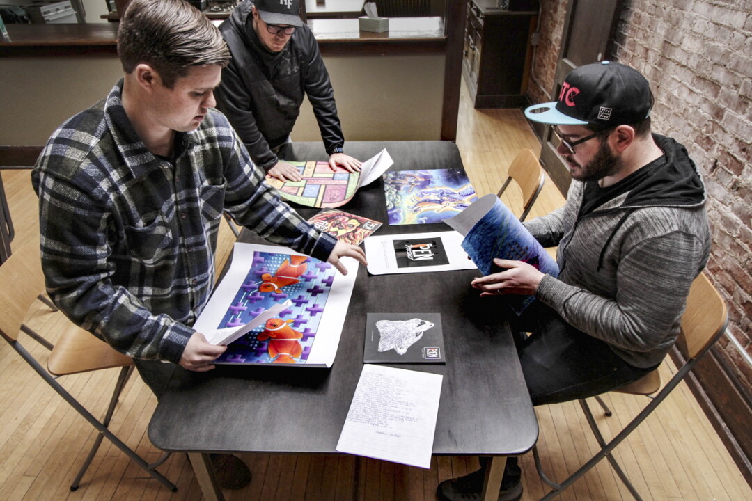 513FREE staff members (left to right) Michael Sandvig, Jesse Hamble, and Jonny Stoll look over works of art submitted by inmates for The Pen Project magazine.