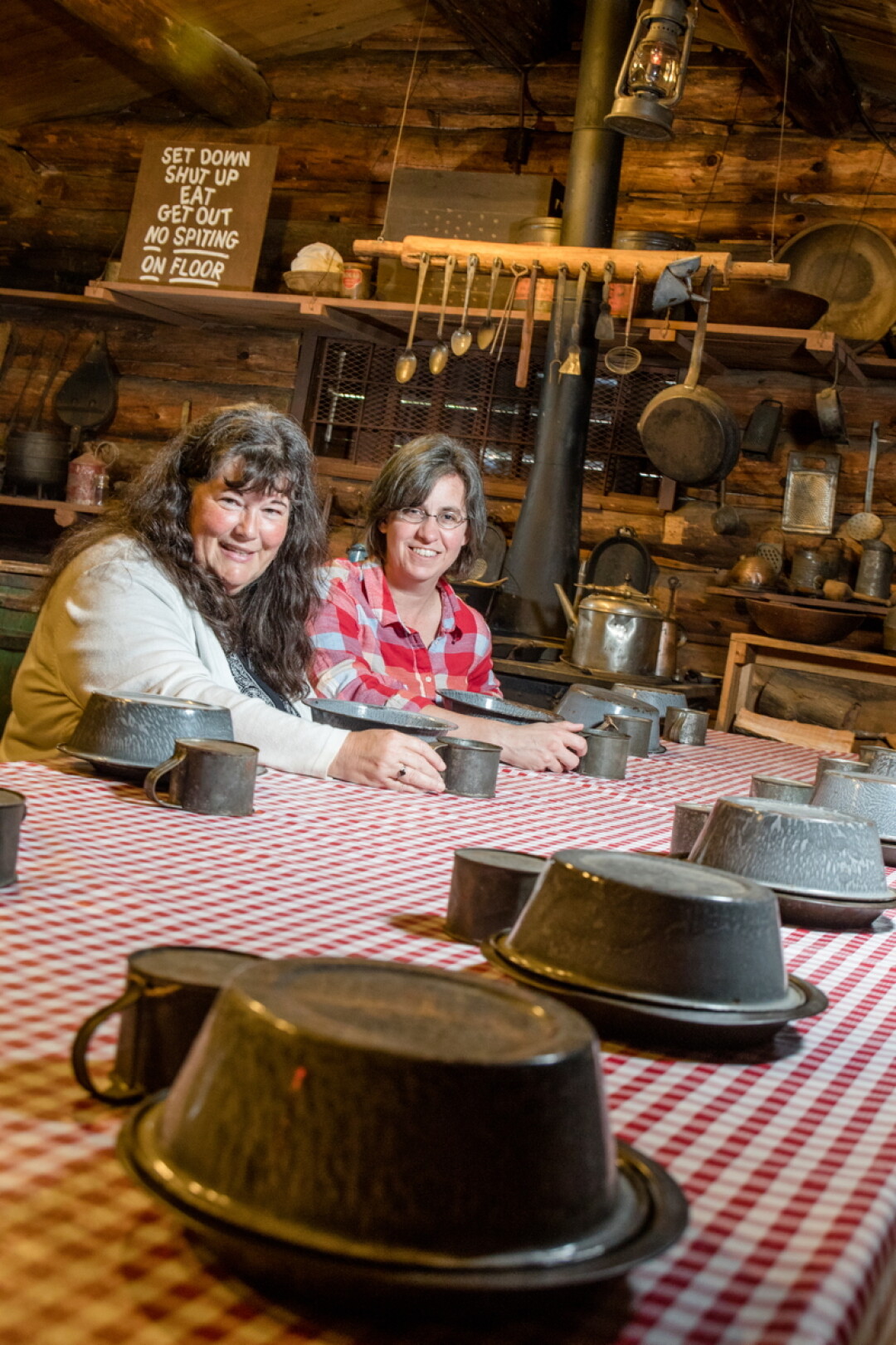 WAITING FOR THEIR FLAPJACKS. Diana Peterson and Carrie Ronnander, co-authors of Logging in Wisconsin, pose inside the cook shanty at the Paul Bunyan Logging Camp Museum in Eau Claire.
