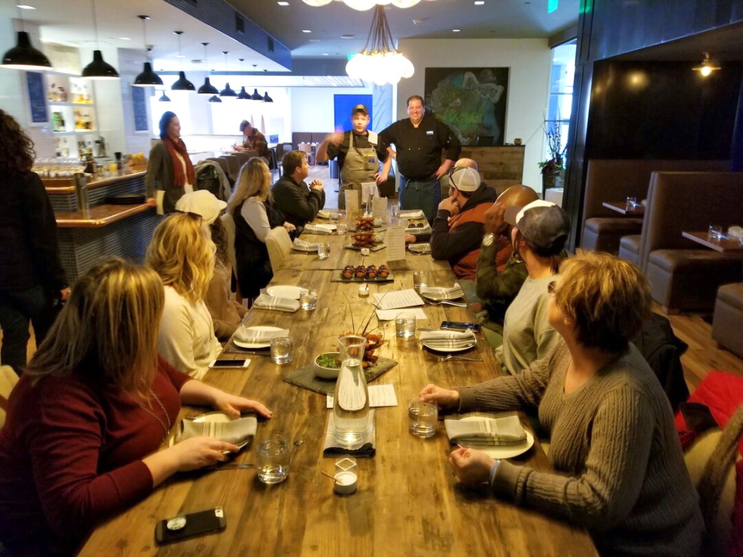 EATING UP HIS WORDS. Participants on a recent Downtown Eau Claire Food and History Tour listened before sampling at The Informalist, 205 S. Barstow St.