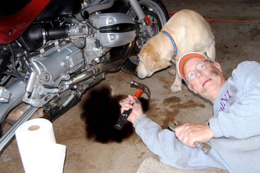 THE RIGHT TOOL FOR THE JOB? Ron Davis attempts to address a mechanical issue on his BMW motorcycle while his dog, Scott, looks on. Davis’ new book, Shiny Side Up, chronicles his motorcycle misadventures.