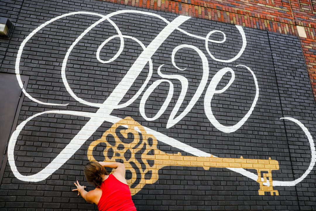 Artist Rehannah Petska at work on her mural on the back of The Metro in downtown Eau Claire.