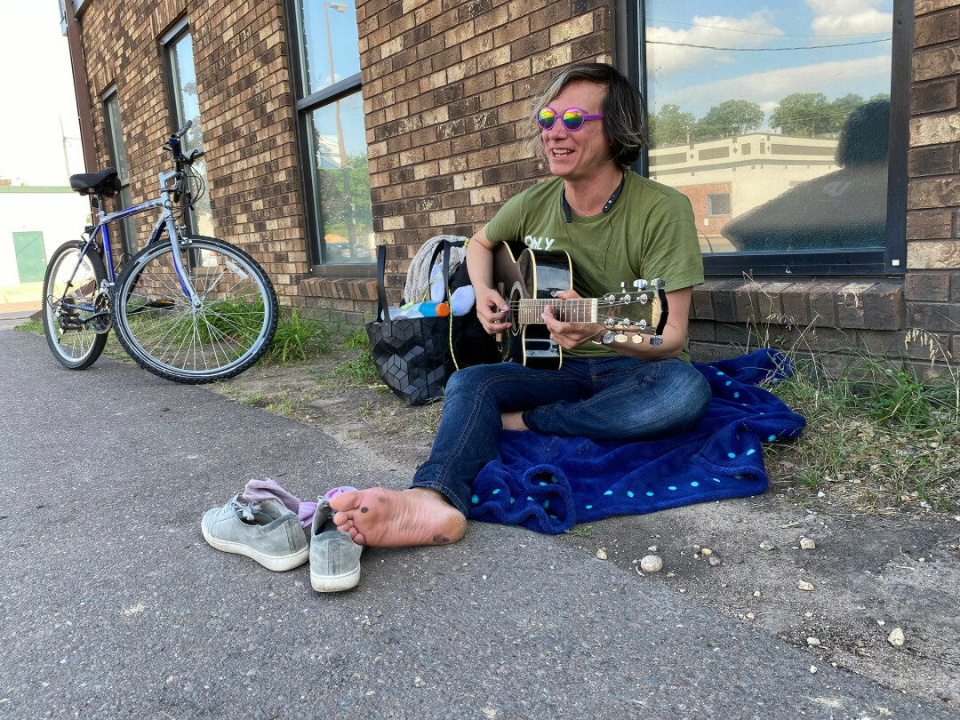 Ellie Burns plays guitar and sings outside of the Sojourner House homeless shelter in downtown Eau Claire on a recent evening. Leaders of local agencies who work with homeless people say that population appears to have grown during the coronavirus pandemic and more resources and new approaches are needed to more effectively address their needs.