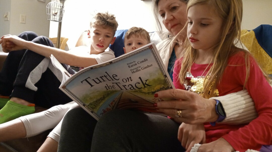 SPREADING JOY WITH EVERY WORD. Katie Condit reads her new book, Turtle on the Track, with her three grandchildren. (Submitted photo)