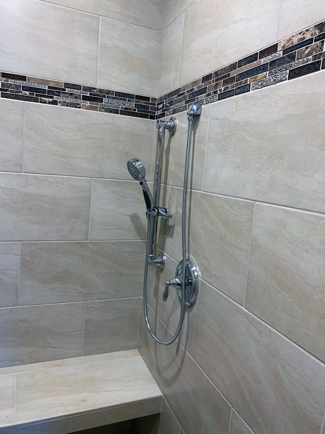 RIGHT: This shower was designed around the needs of the user, including a bench placed at the proper height, open space under the bench for the user’s legs, a shower wand handle that is also grab bar, and more.