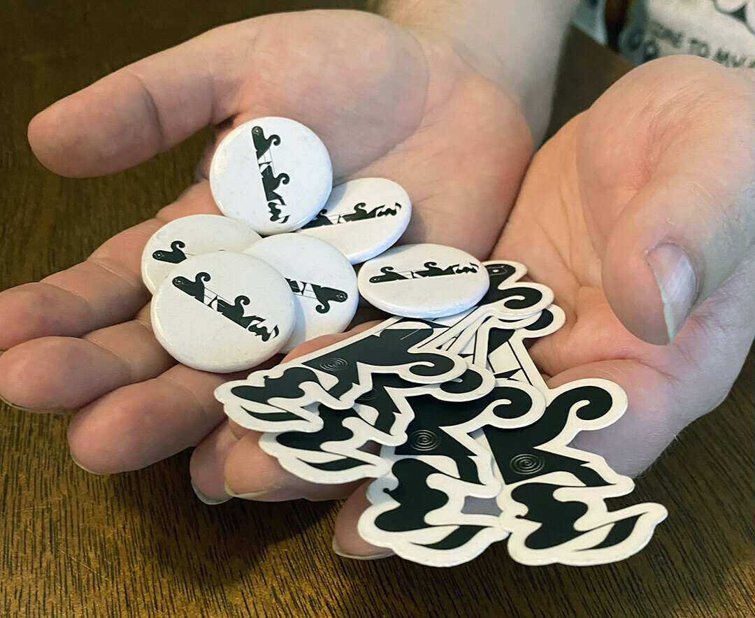 Evan Minsker holding see/saw stickers and buttons, photo by Morgan Barrie