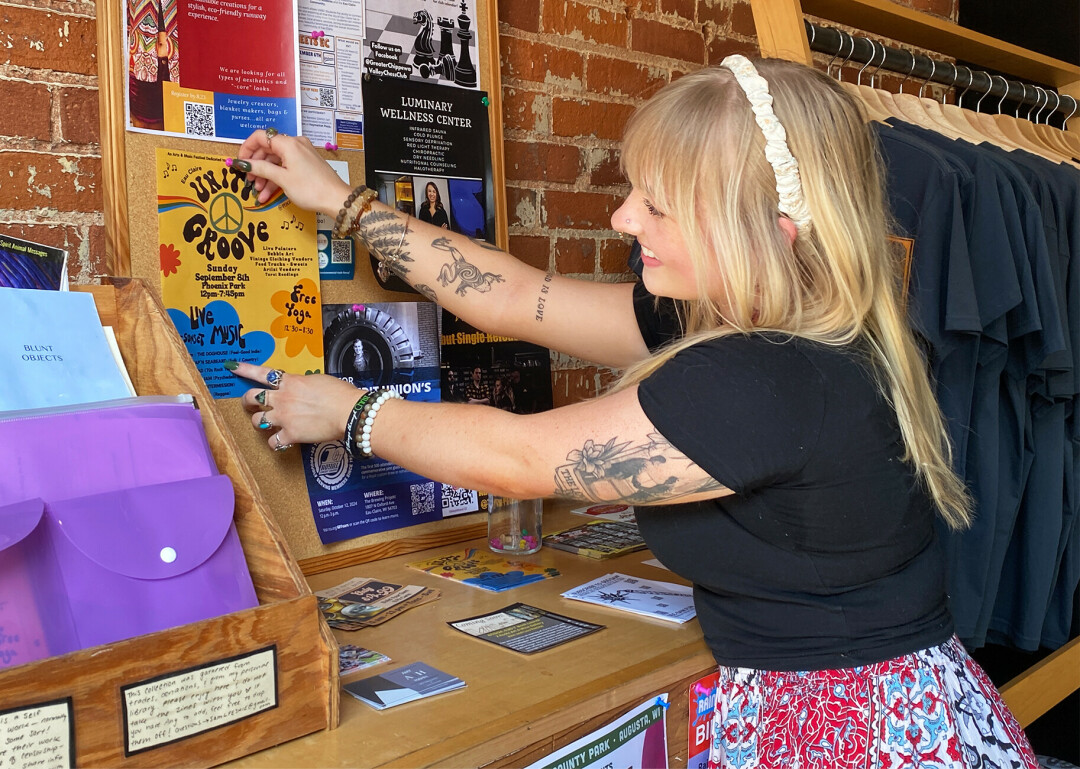 Faith Freedlund, creator of the Unity Groove event, posts a promotional flyer on a community bulletin in downtown Eau Claire. This event fosters messages of inclusivity, artistic expression, and unity across various backgrounds and disciplines, she said.