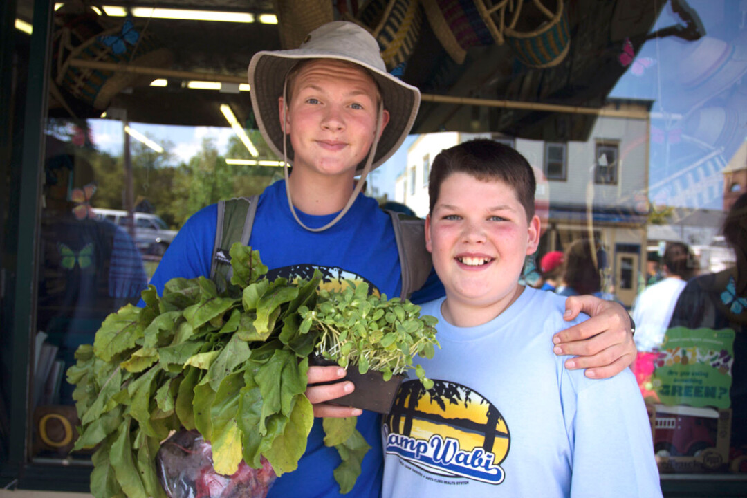 Camp counselor Jonah Giese, left, and camper Matthew Jacobs found fresh produce to purchase at a farmers market field trip, an outing for Camp Wabi.